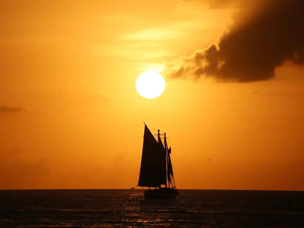 A schooner silhouetted against an orange sunset off Key West.